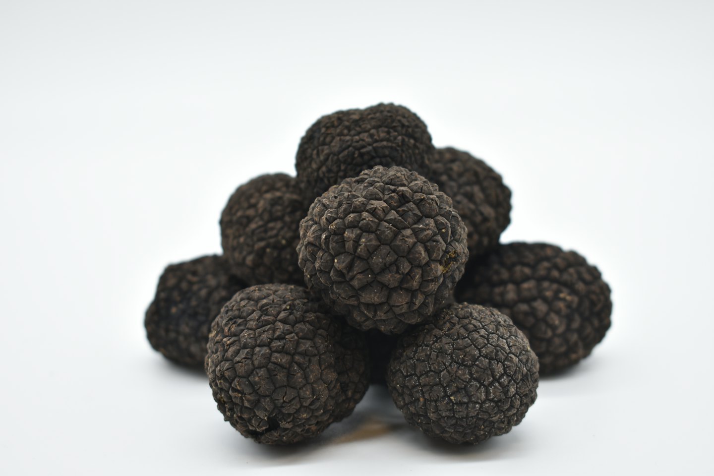 A small pile of rough black truffles on white surface.
